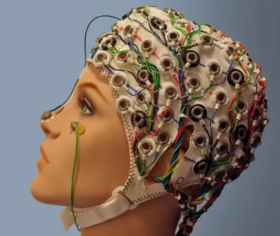 A plastic mannequin with an EEG headset and lots of wires attached.