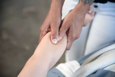 MT pressing on a client's forearm area with two thumbs, one on top of the other.