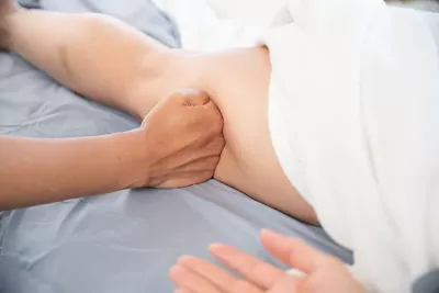 an MT using their fist to gently glide over an area on a client's leg. 