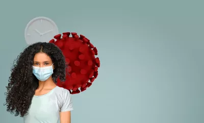 A woman with curly long hair wearing a face mask stands in front of a cartoon red cell.