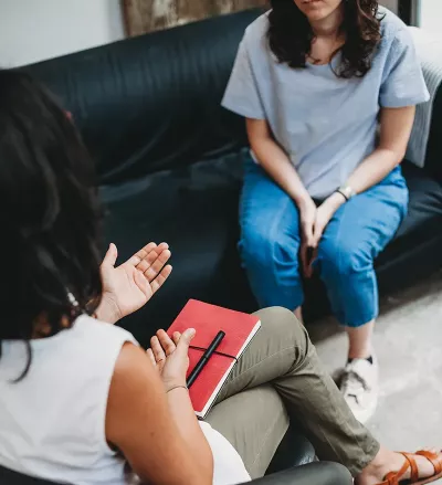 A therapist in a chair consults with a client on a couch.