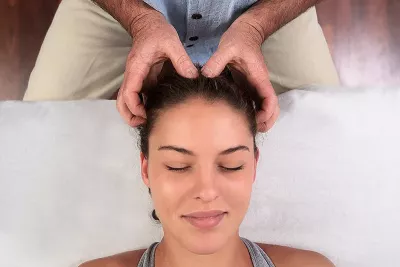 an MT demonstrating the parietal technique on the head of a female client.