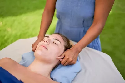 A massage therapist addresses a female client's ears during a massage session.