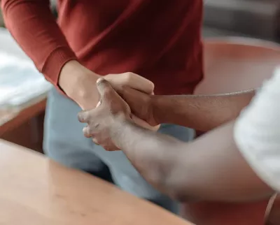 Two people shake hands, one of them using two hands.