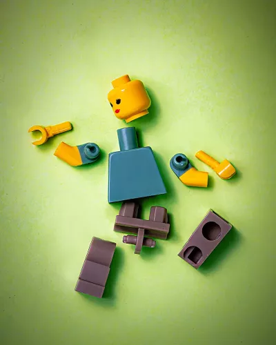 A LEGO figure of a person with all the parts unattached and scattered.