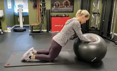 Author Marisa Savino demonstrates pushing on a fitness ball, with her hips positioned forward.