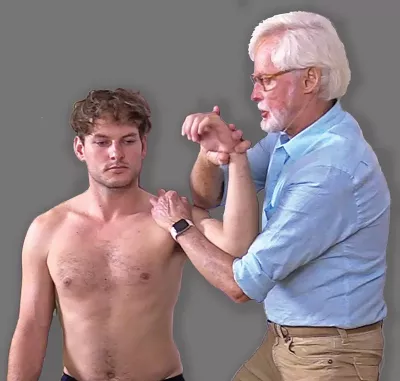 Erik Dalton performing internal/external rotations on a shirtless male client.