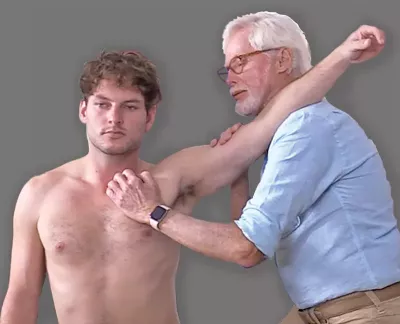 Erik Dalton performing internal/external rotations on a male client with his arm extended above his head.