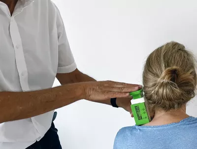 A therapist uses a device to measure myofascial tissue properties on a client.