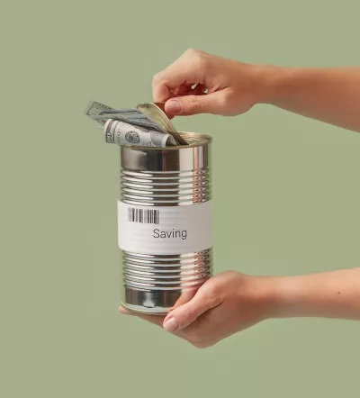 Two hands opening and holding a tin can filled with cash.