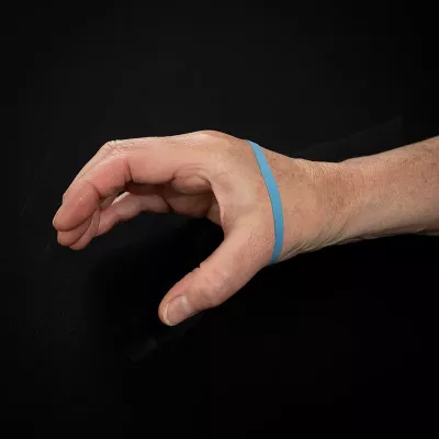 Demonstration of exercise for the thumb with rubber band around the hand and fingers, with the hand opened in a 