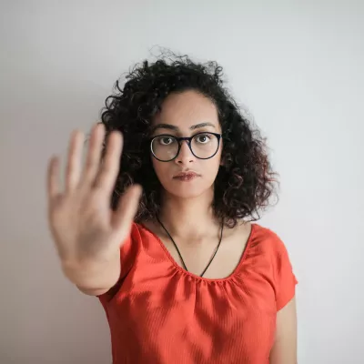 A woman with glasses stands with her arm outstretched in a
