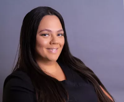 carol reyes ryan with long dark hair smiles for a photo.