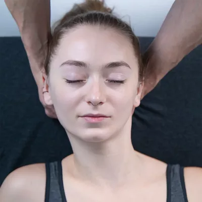 A massage therapist demonstrates a manual version of belly dancer head slides on a female client.