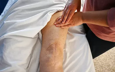 A massage therapist massages a client's upper leg.