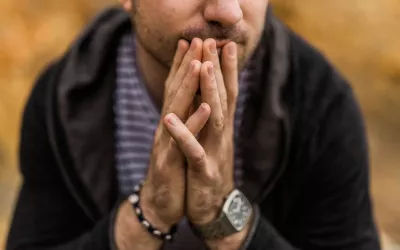 A man holds his hands together in front of his face.