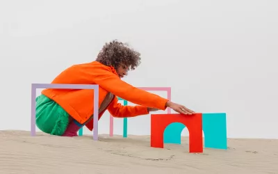 A woman adjusts miniature archways in the sand.