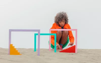 A woman adjusts a miniature staircase and archways.