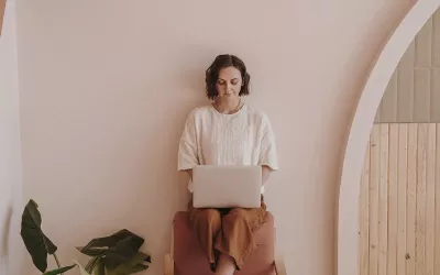 A woman sits on a chair while working on her laptop. 