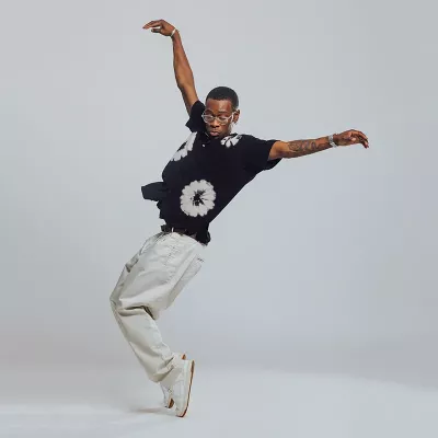 A man performs a hip-hop dance technique, standing on his toes.