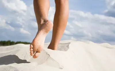 Two feet walking through a sand dune.