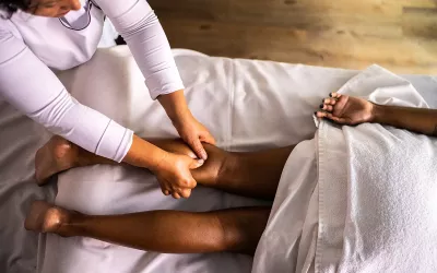 A massage therapist works on a client's calf.
