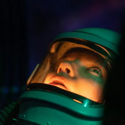 A person in a deep-sea diving suit stares into the depths.